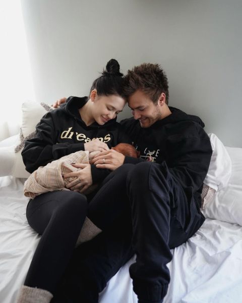Peyton Meyer and Taela holding their child